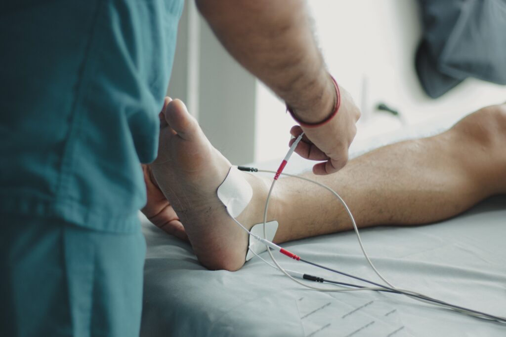 Fisioterapia Avanzada Close-up of a healthcare worker examining a patient's foot with medical equipment in a hospital setting.
