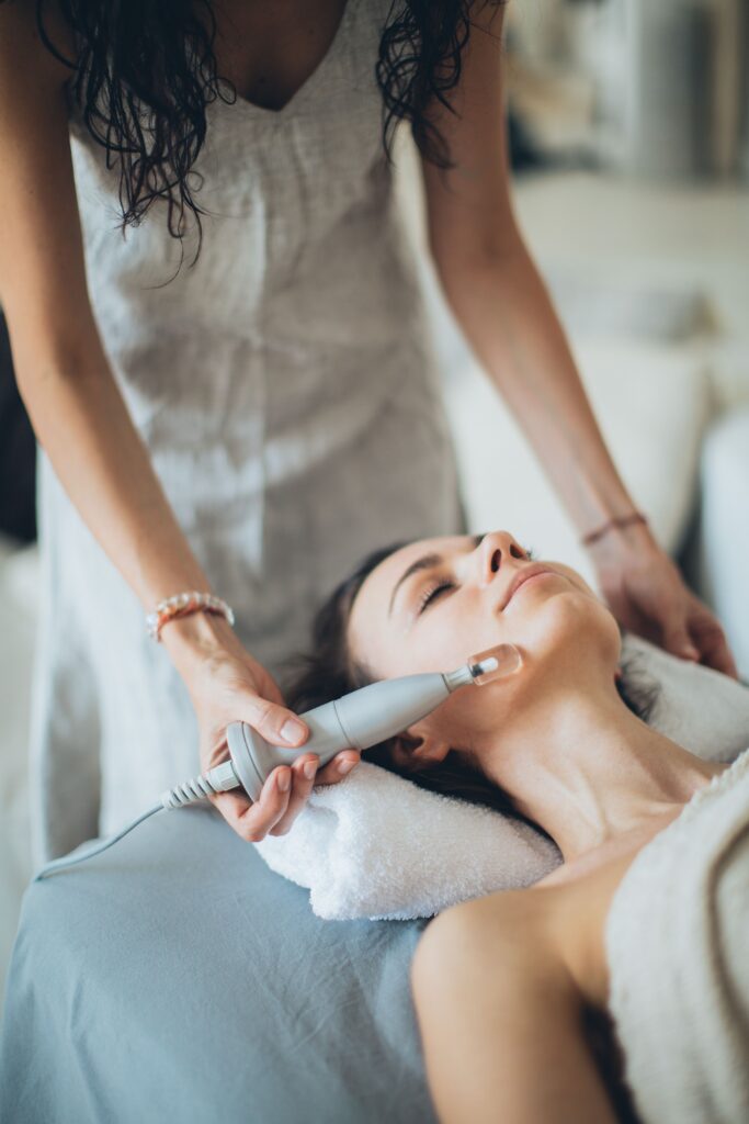 Services A woman enjoying a relaxing facial treatment using advanced technology at a spa. Perfect for wellness promotion.