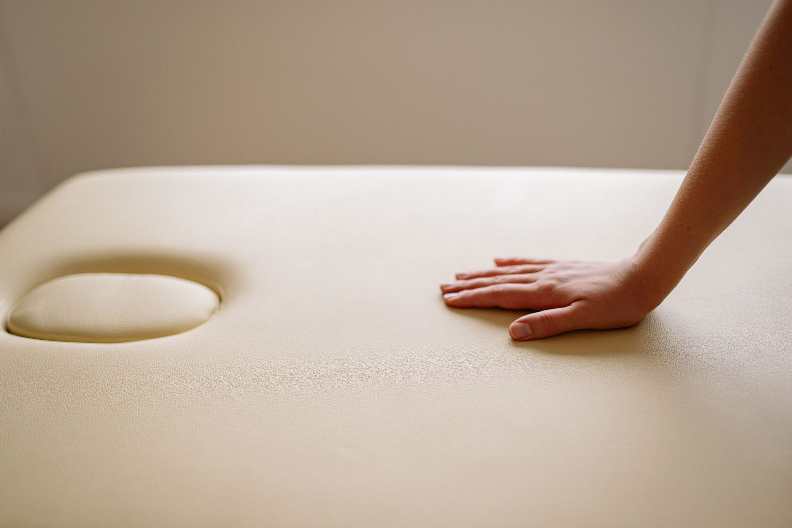 INICIO A close-up image of a hand gently pressing on a soft leather surface, showcasing texture and comfort.