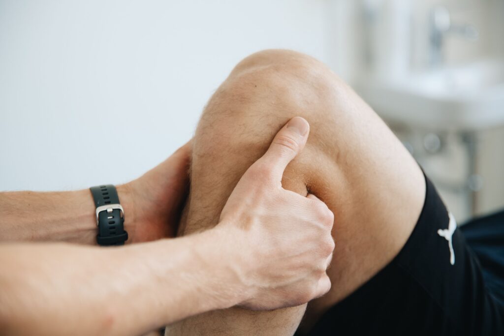 Fisioterapia Deportiva Close-up of a physiotherapist massaging a patient's knee during therapy.